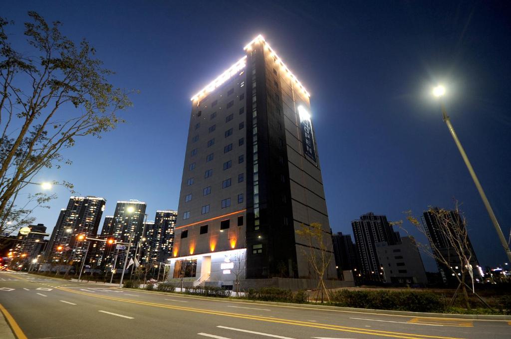 a tall building with lights on it on a city street at Gijang Hound Hotel Ilgwang in Busan