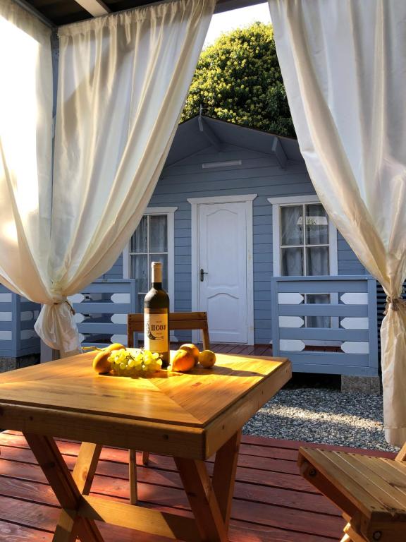 a table with a bottle of wine and fruit on a patio at Эко домики у моря в Гаграх in Gagra