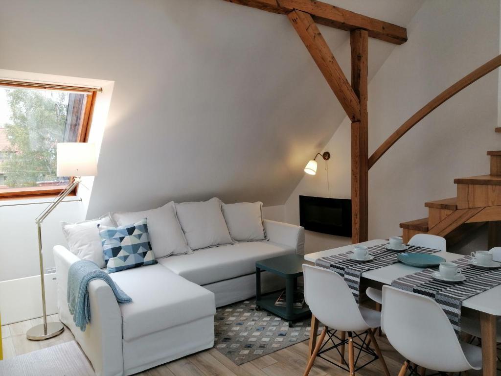 a living room with a white couch and a table at Apartamentai Niden - su terasa ir vaizdu i marias Nidos centre in Nida