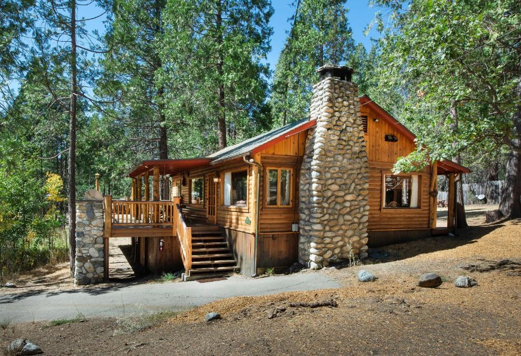 a log cabin in the woods with a stone chimney at 72 Sequoia in North Wawona