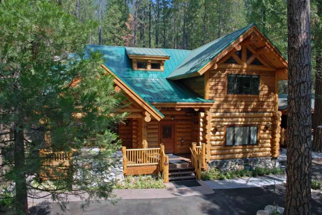 une cabane en rondins dans les bois avec un toit vert dans l'établissement 67 El Capitan, à North Wawona