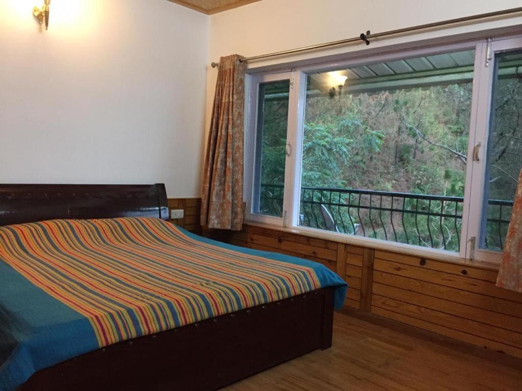 a bedroom with a bed and a large window at Joule's Cottage, Independent Cottage in Barog
