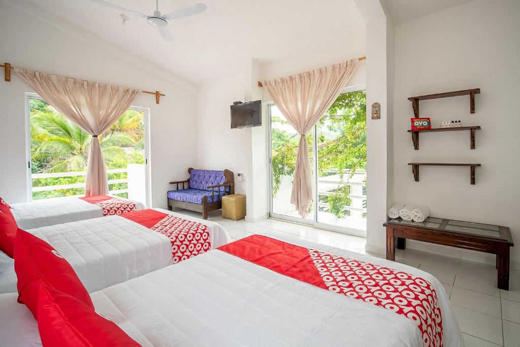 1 dormitorio con 2 camas con sábanas rojas y blancas en OYO Hotel Posada San Vicente, Huatulco en Santa María Huatulco