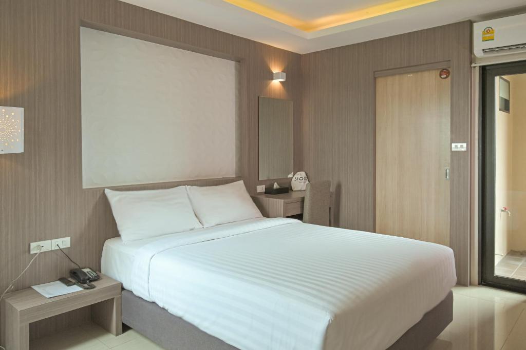 um quarto com uma grande cama branca e duas mesas em Sleep Hotel Bangkok em Bangkok