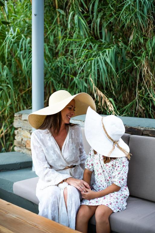 a woman sitting next to a little girl wearing a hat at Gianemma Luxury Apartments in Mylopotas