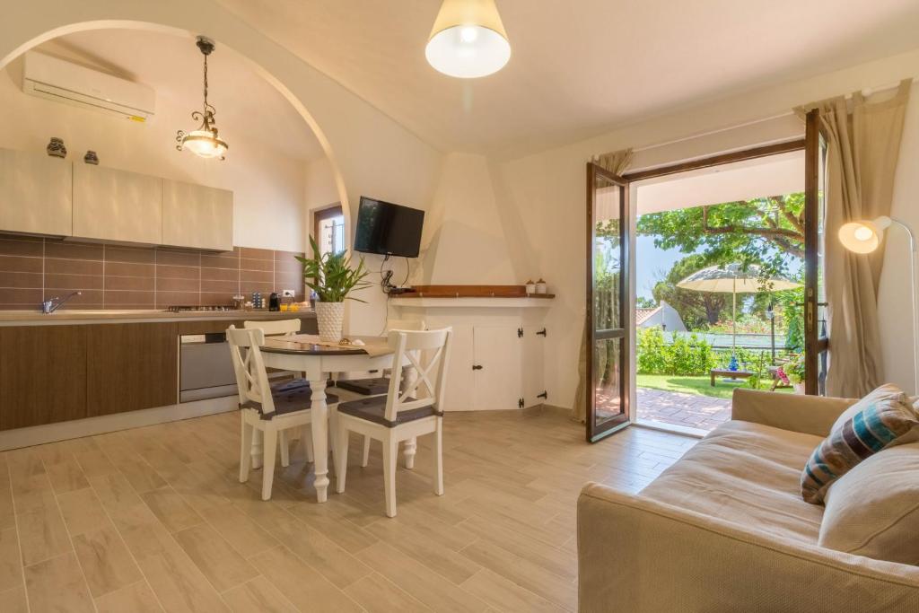 kuchnia i salon ze stołem i kanapą w obiekcie Casa Azzurra - Casa con giardino privato a Costa Rei a due passi dal mare w mieście Costa Rei