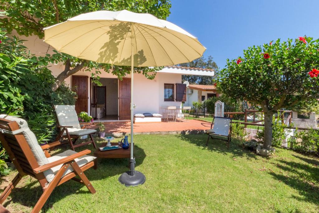 eine Terrasse mit Stühlen und einem Sonnenschirm im Hof in der Unterkunft Casa Azzurra - Casa con giardino privato a Costa Rei a due passi dal mare in Costa Rei