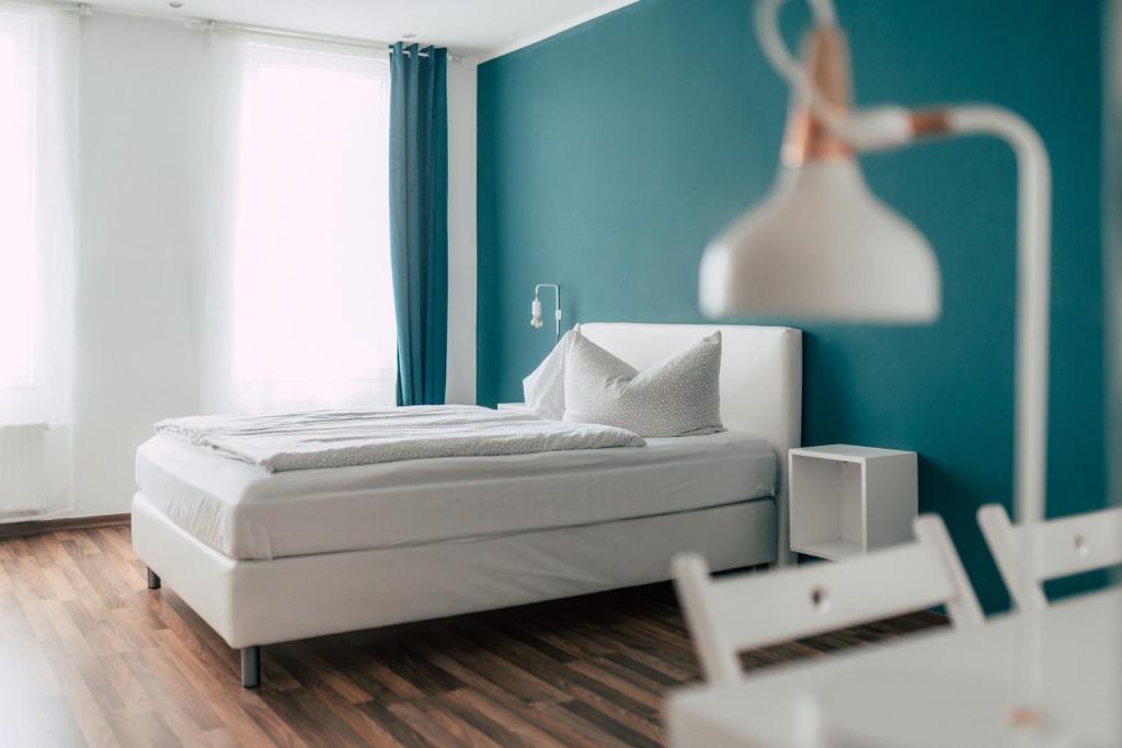 a bedroom with a white bed and a blue wall at Hentschels Apartments in Leipzig
