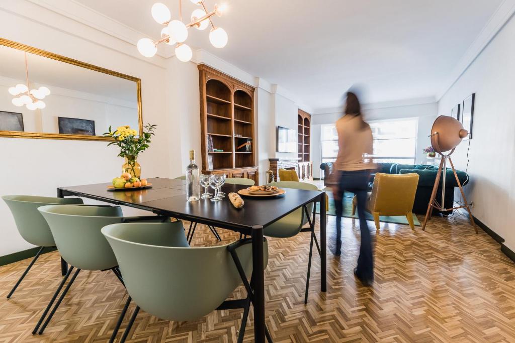 een vrouw die door een woonkamer loopt met een tafel en stoelen bij ZUBIETA PLAZA Apartment in San Sebastian