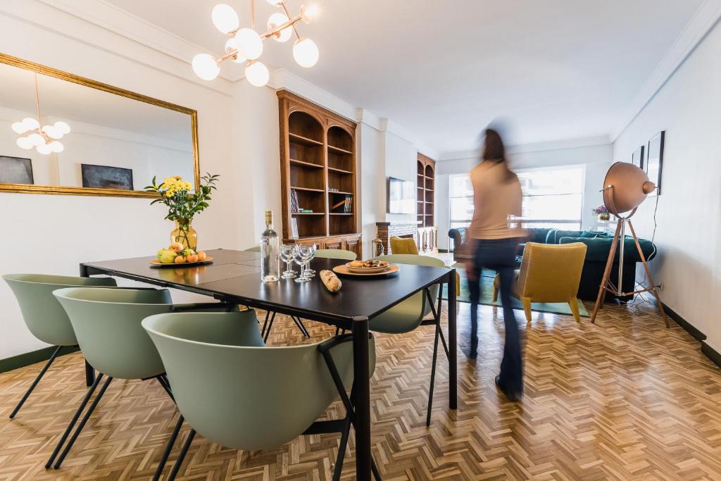 kobieta przechodząca przez salon ze stołem i krzesłami w obiekcie ZUBIETA by SWEET HOME SAN SEBASTIAN w mieście San Sebastián