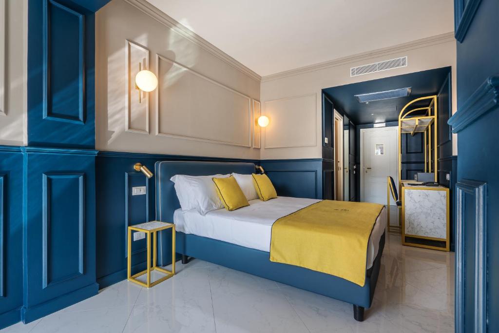 een slaapkamer met blauwe muren en een bed met een gele deken bij Hotel Mary in Vico Equense