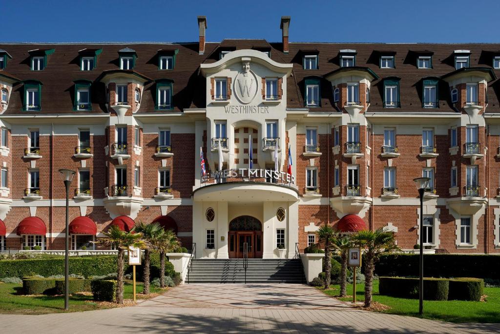 a large red and white building with stairs leading to it at Hôtel Barrière Le Westminster in Le Touquet-Paris-Plage