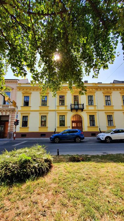 una macchina blu parcheggiata di fronte a un edificio giallo di Apartmani Galea a Sombor