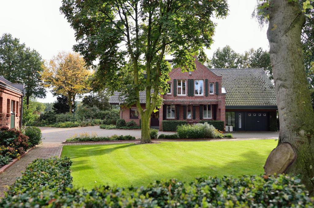 uma casa com um relvado verde em frente em Große Ferienwohnung, auf Bauernhof mit Ponys und Pferden, ländlich und ruhig, Nähe Dümmer See em Holdorf