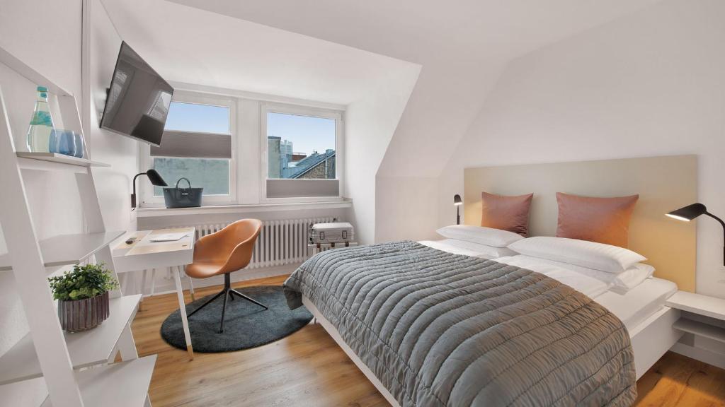 Beethoven Hotel Dreesen - furnished by BoConcept في بون: غرفة نوم بيضاء بها سرير ومكتب ونافذة