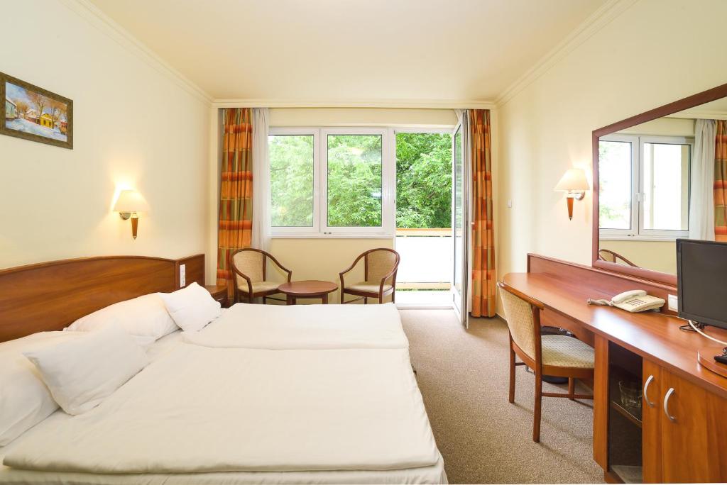 Cette chambre comprend deux lits et un bureau. dans l'établissement Hungarospa Thermal Hotel, à Hajdúszoboszló