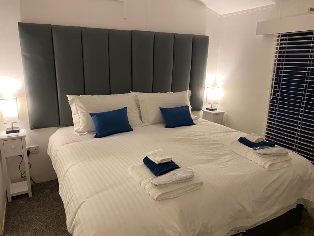 a bedroom with a large white bed with blue pillows at Loxley's Devon Lodge in Brixham