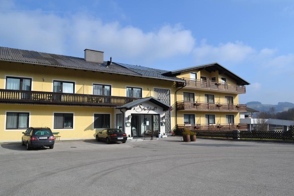 un gran edificio amarillo con coches aparcados en un aparcamiento en Gasthof s'Schatzkastl, en Ardagger Markt