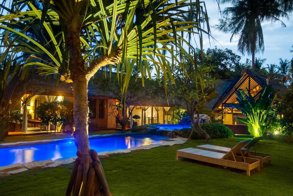 a villa with a swimming pool at night at Dolcemare Resort in Gili Islands