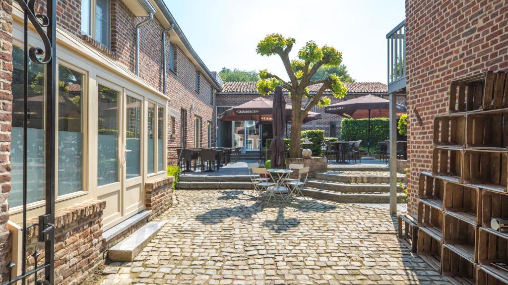 a courtyard with a brick building and a tree at Hoeve de Sterappel in Tongeren