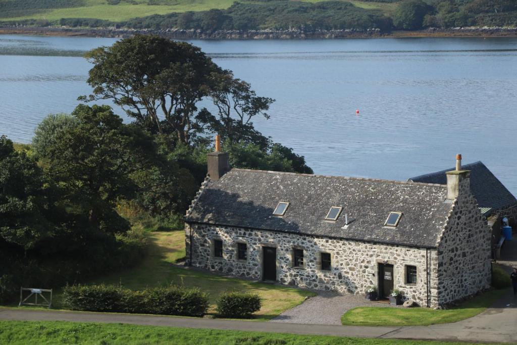 an old stone house on the shore of a lake at Dunvegan Castle Laundry Cottage in Dunvegan