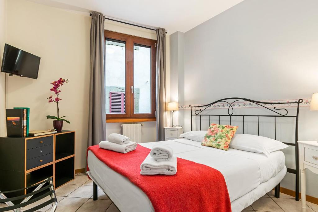 Borgo Pinti Cozy Flat في فلورنسا: غرفة نوم بسرير وفوط على بطانية حمراء
