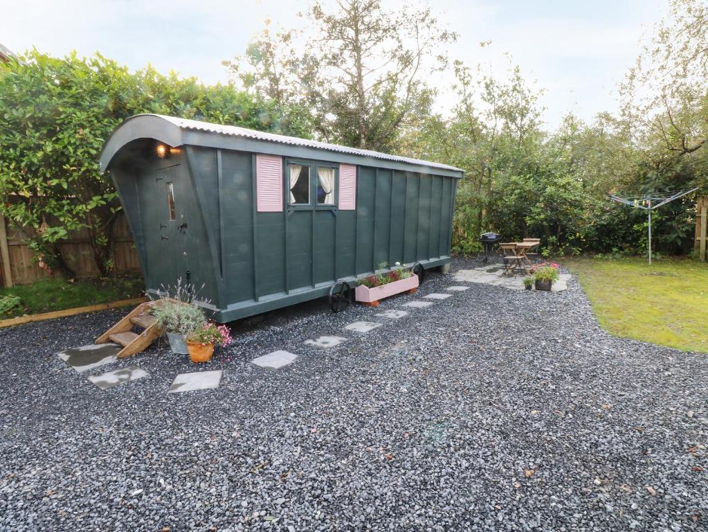 a green tiny house sitting on top of gravel at Hazel Nook in Narberth