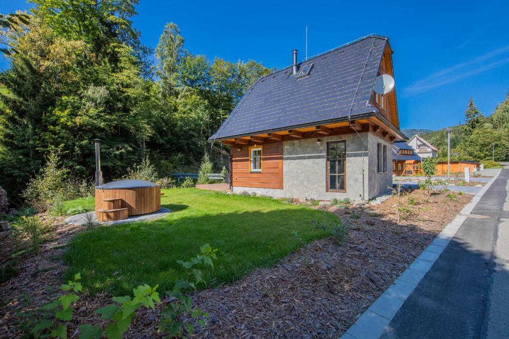 a small wooden cabin with a green yard at Chatička u řeky - Kouty nad Desnou in Loučná nad Desnou