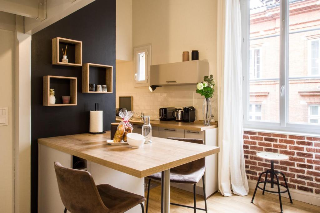 a kitchen with a table and chairs and a brick wall at So Sweet Capitole in Toulouse