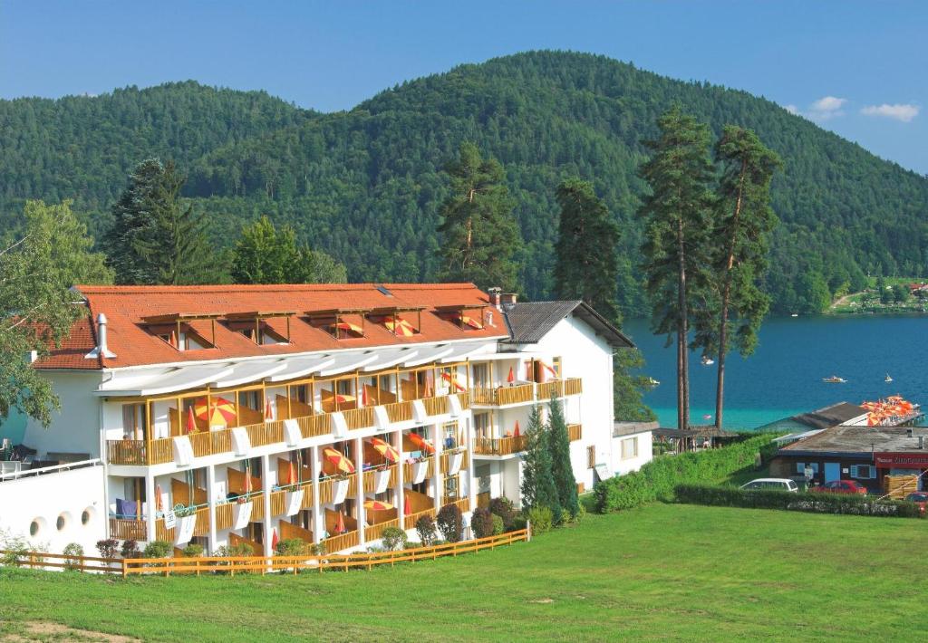 a hotel on a hill with a lake in the background at Terrassenhotel Reichmann in Sankt Kanzian