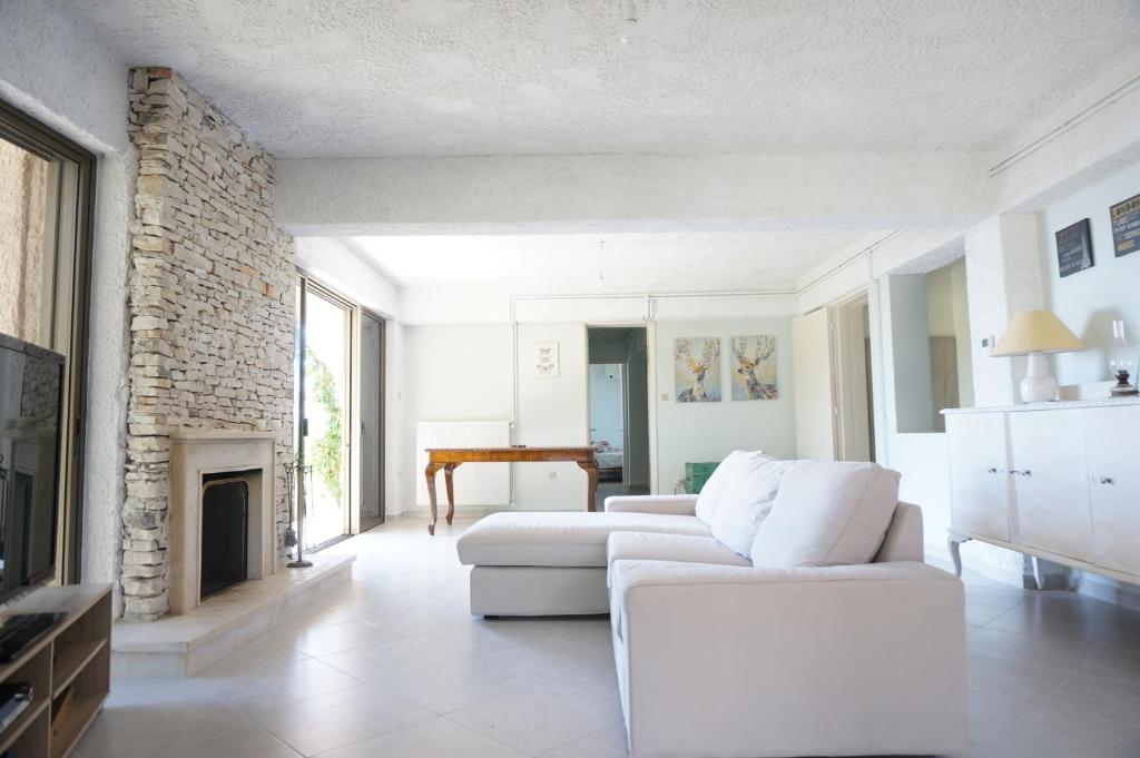 a living room with a white couch and a fireplace at Kefalonia Sea View Cottage in Áno Váltai