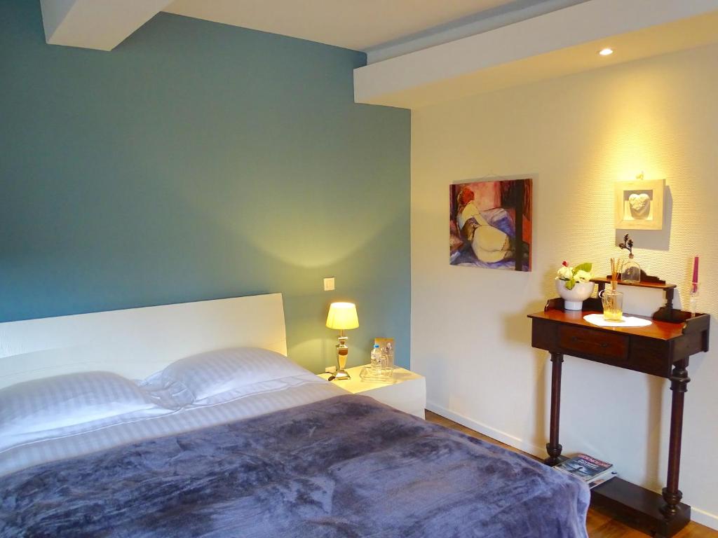 een slaapkamer met een groot bed en een tafel bij Les Myosotis Chambres d'hôtes - Sarreguemines in Zetting