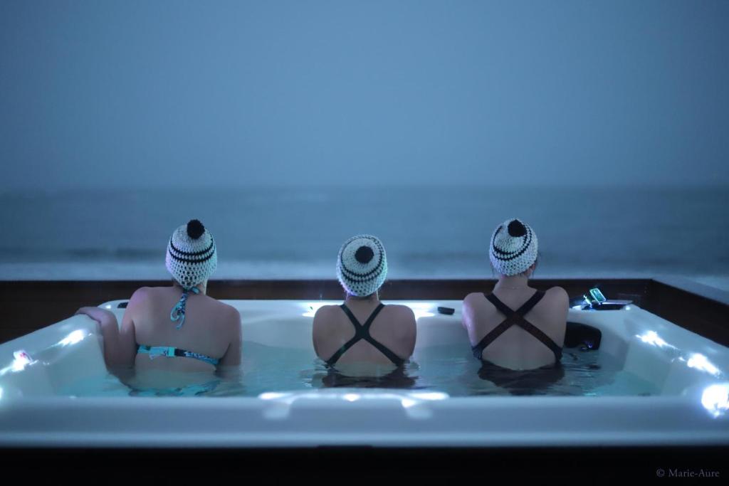 3 persone sedute in una vasca da bagno con una luce blu di Stave Camping & Hot Pools a Stave
