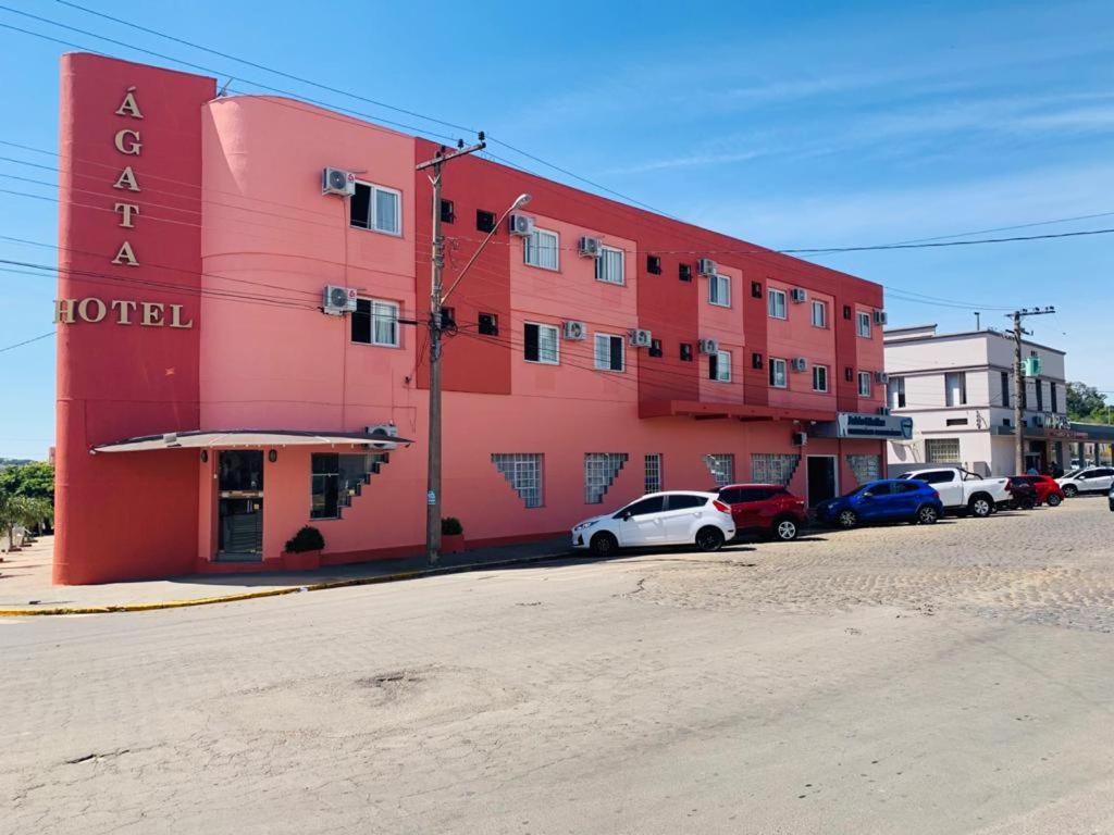 un edificio rojo con coches estacionados frente a él en Agata Hotel en Soledade