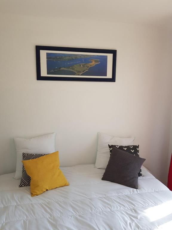 1 cama blanca con almohadas y una foto en la pared en studio front de mer, en Ouistreham
