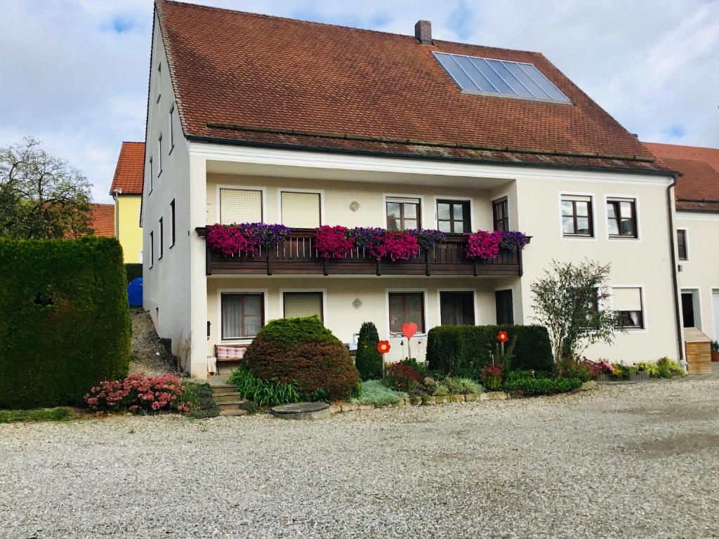 a white house with flowers on a balcony at Ferienwohnung Familie Heigemeir in Ehekirchen
