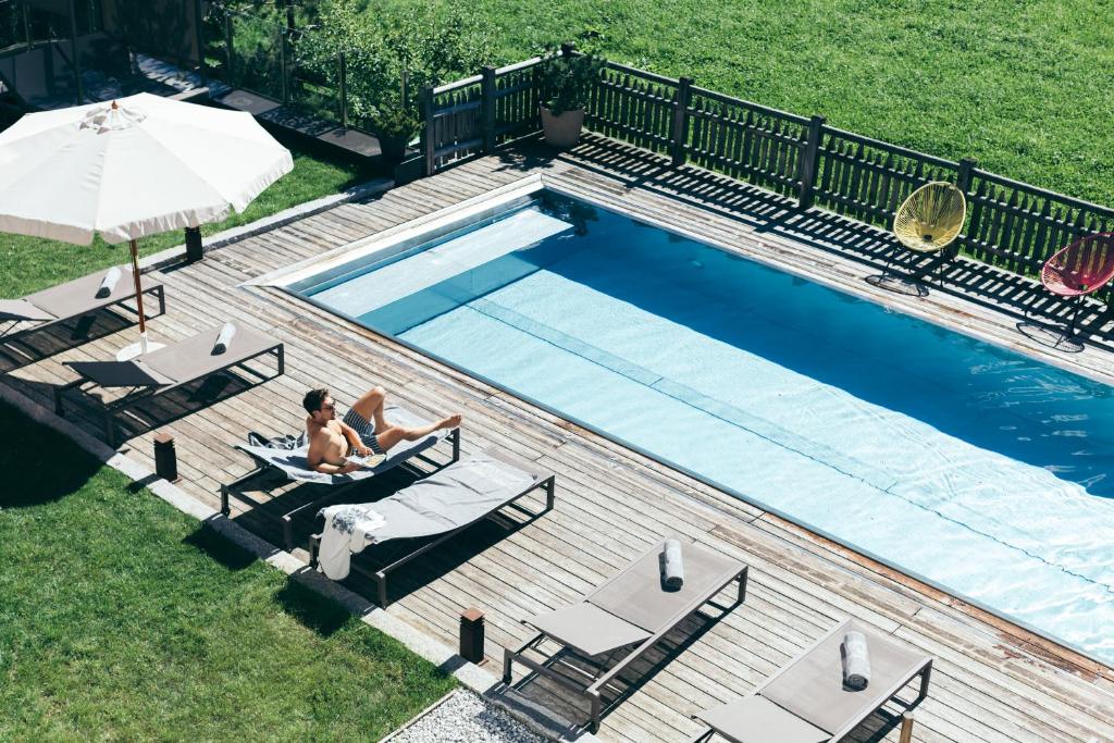 a woman sitting in a chair next to a swimming pool at Boutique Hotel Das Rivus in Leogang