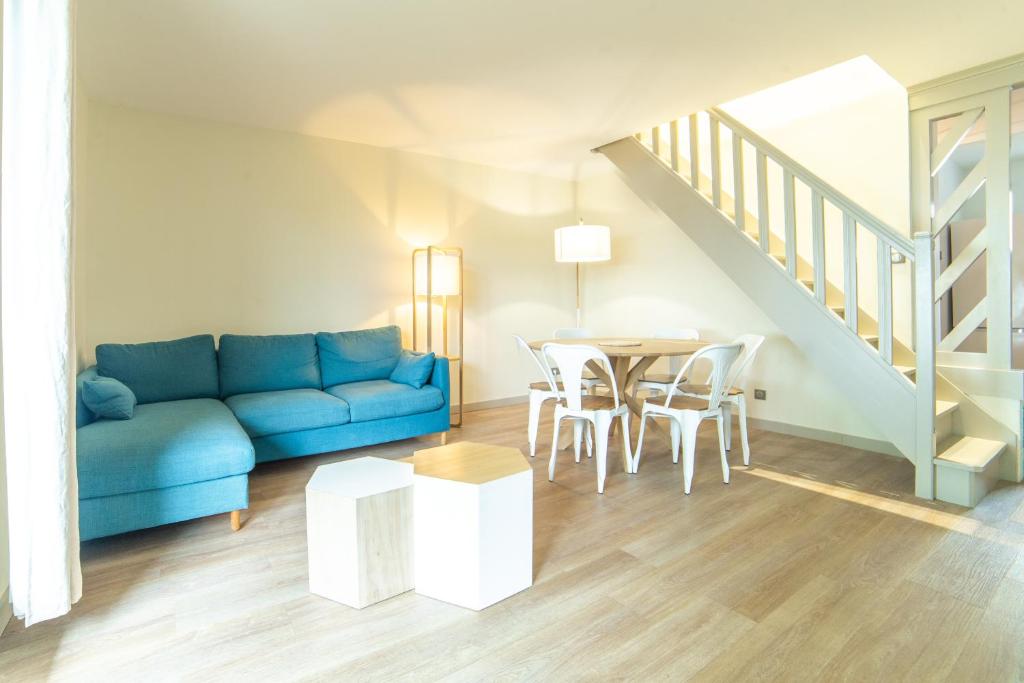 - un salon avec un canapé bleu et une table dans l'établissement Cottage "Le NAUTIC" face au Lac de la forêt d'Orient - Les Cottages du Belvédère, à Mesnil-Saint-Père