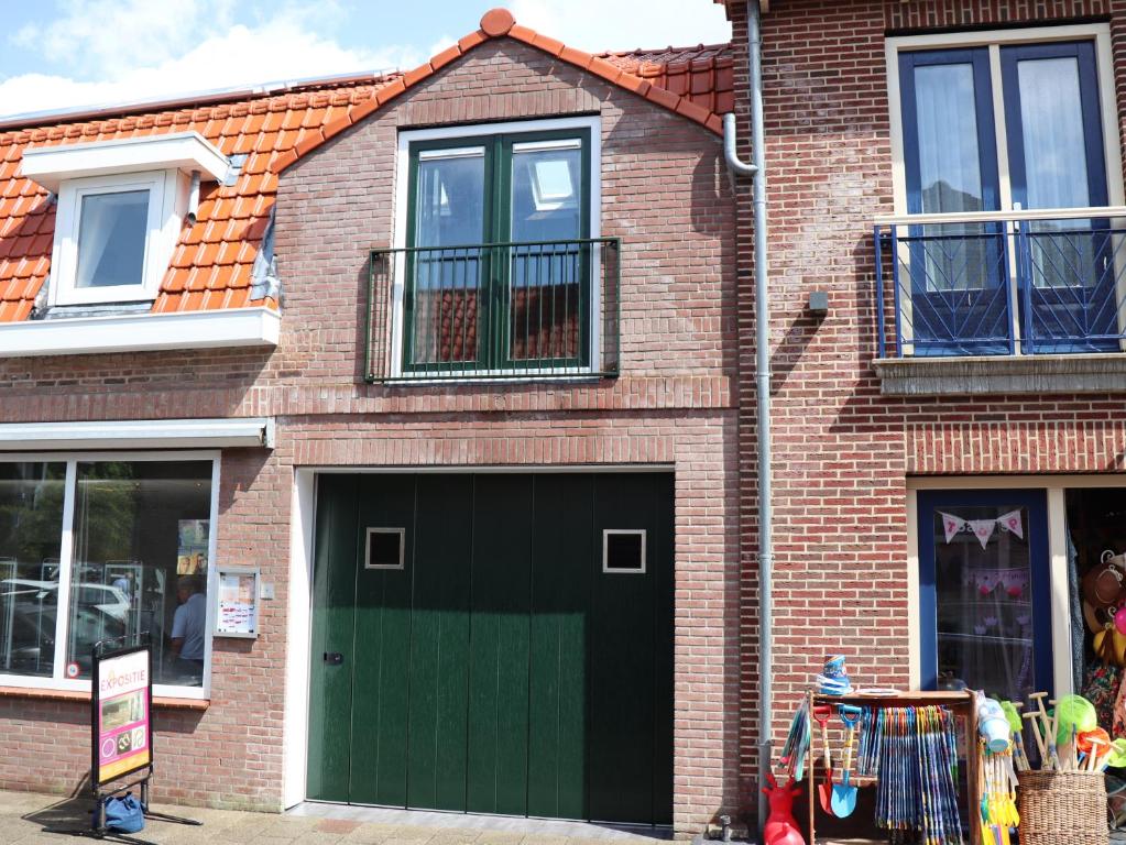 un edificio de ladrillo con una puerta de garaje verde en DortDomburg, en Domburg