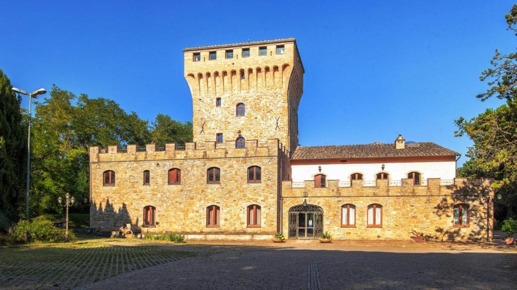 un grande edificio in pietra con una torre sopra di Torrenova di Assisi Country House ad Assisi