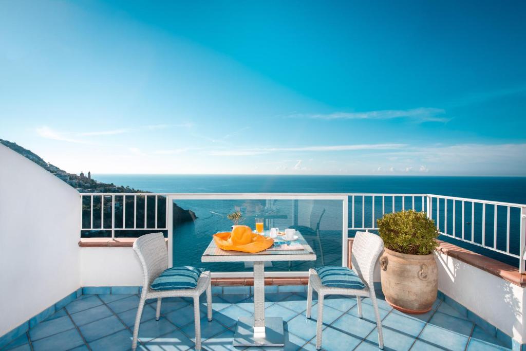 balcone con tavolo, sedie e vista sull'oceano di Grand Hotel Tritone a Praiano