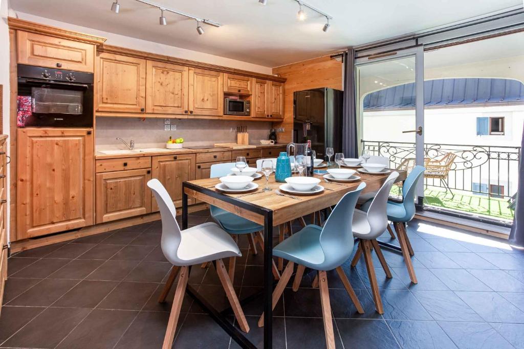 a kitchen with a wooden table and blue chairs at Le Paradis 25 Apartment - Chamonix All Year in Chamonix