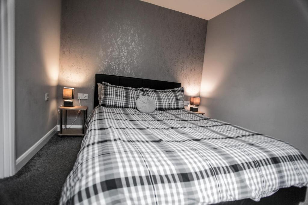 a bedroom with a bed with a plaid blanket and two lamps at No 3 New Inn Apartments NEWLY RENOVATED in Newark-on-Trent