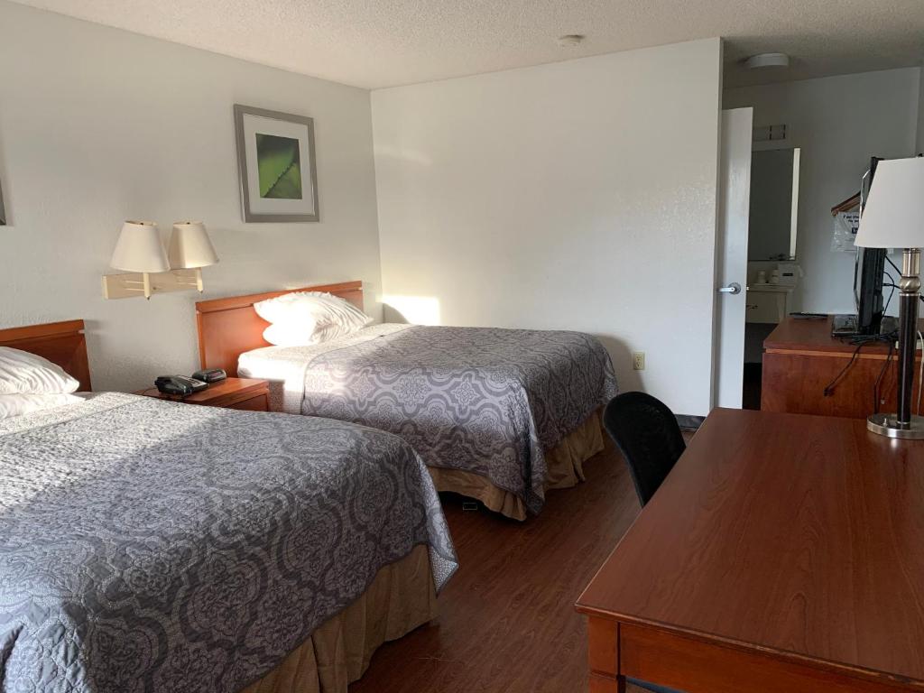 a hotel room with two beds and a table at Travelodge Suites by Wyndham MacClenny I-10 in Macclenny
