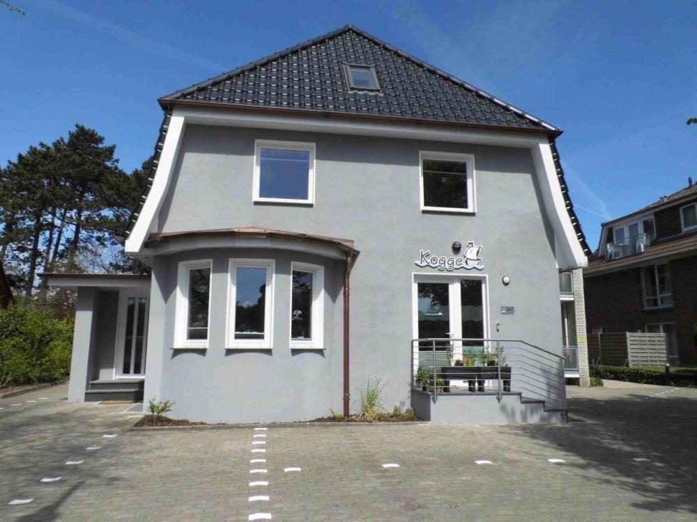 une maison blanche avec un parking en face de celle-ci dans l'établissement Appartementhaus-Kogge-Wohnung-7, à Cuxhaven