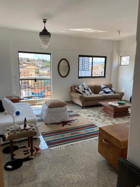 a living room filled with furniture and a large window at Lindo apartamento em Caxambu in Caxambu