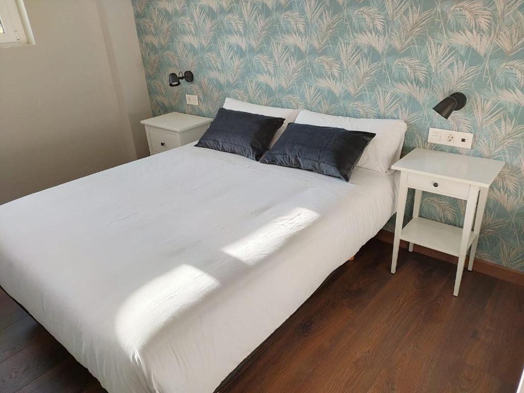1 dormitorio con 1 cama blanca grande y mesita de noche en Pensión Boutique AdMera Cerca hospital Clínico, en Santiago de Compostela