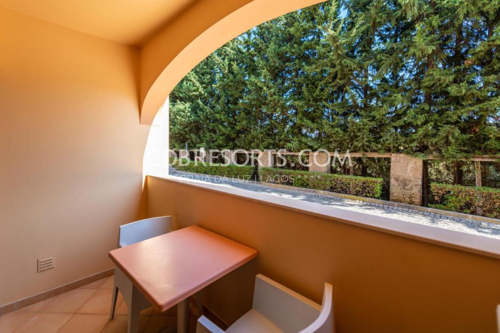 a small table and chairs in a room with a window at Baia da Luz Resort in Luz