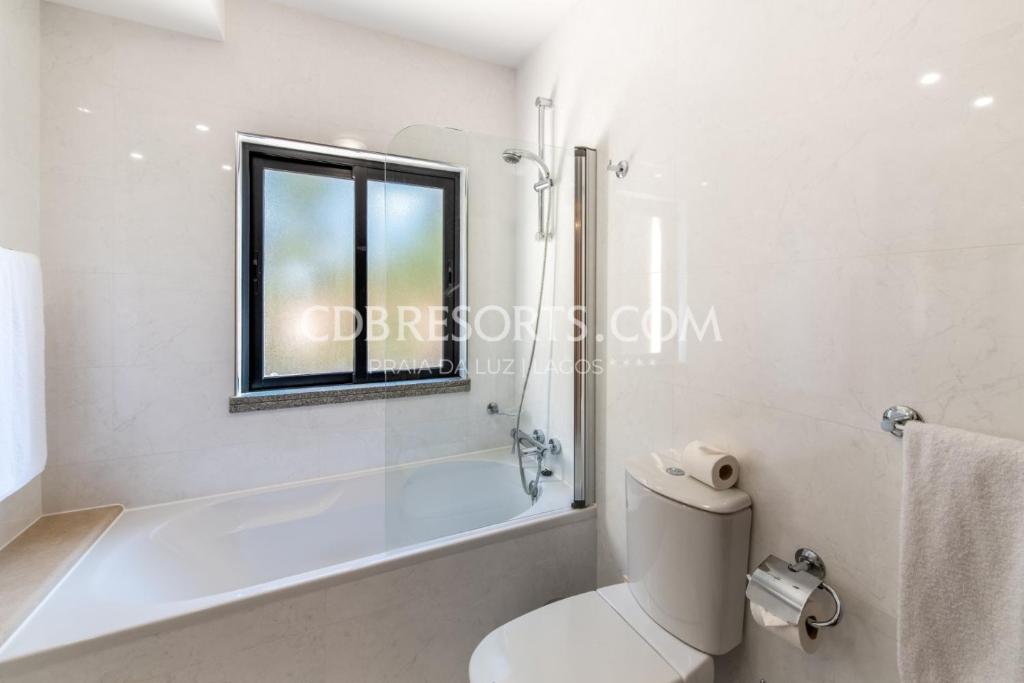 a bathroom with a tub and a toilet and a window at Baia da Luz Resort in Luz