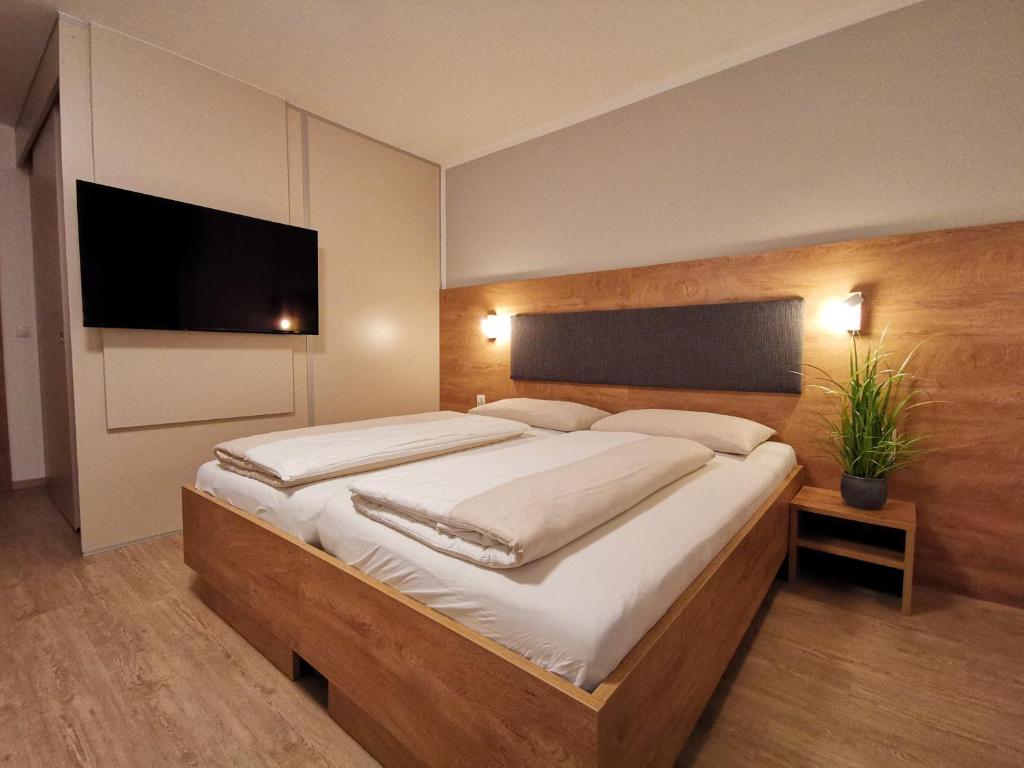 a bedroom with a large bed and a flat screen tv at Motel Hohenems in Hohenems